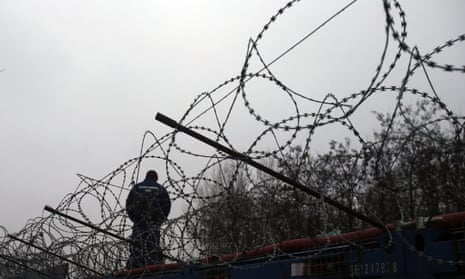 A Hungarian police officer stands guard at Serbia’s border with Hungary near a makeshift camp in Horgos in February.