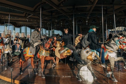 People ride an old-style wooden worse carousel.