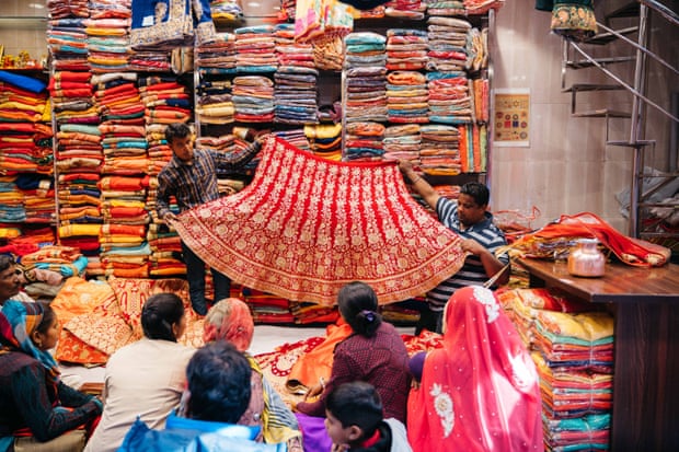 Two men hold out a piece of textile in front of a group of customers in Jaipur, India.
