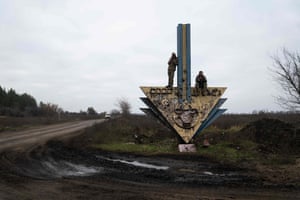 Ukrainian servicemen stand and sit on a structure trying to catch a mobile network signal near the border between the regions of Kharkiv and Donetsk