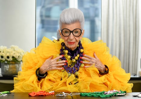 Iris Apfel at 100 in large black spectactles and yellow organza frilled dress and lots of beads
