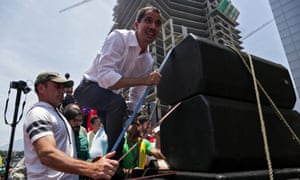 Juan Guaidó climbs up a makeshift stage during a rally to commemorate May Day in Caracas.
