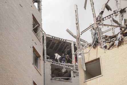 View looking up at civilian rescuers standing on top floor of the blown-out building
