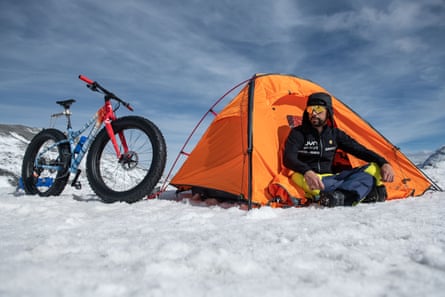 Di Felice sits in front of an orange tent pitched in the snow