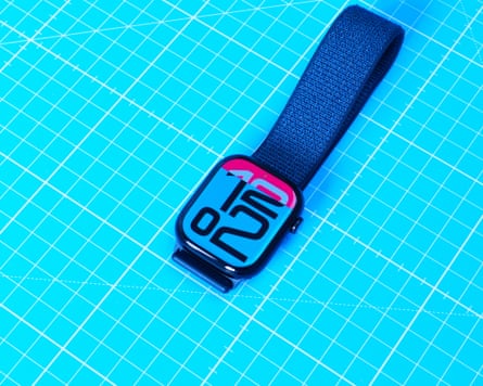 An Apple Watch 10 with deep blue strap and light blue face sits on top of a bright blue and white grid surface.