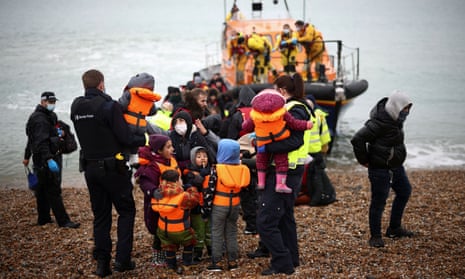 People who crossed the Channel in a small boat are helped ashore by RNLI and Border Force staff at Dungeness in Kent on 24 November.