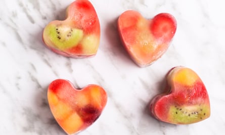 Heart-shaped ice cubes with frozen fruit pieces