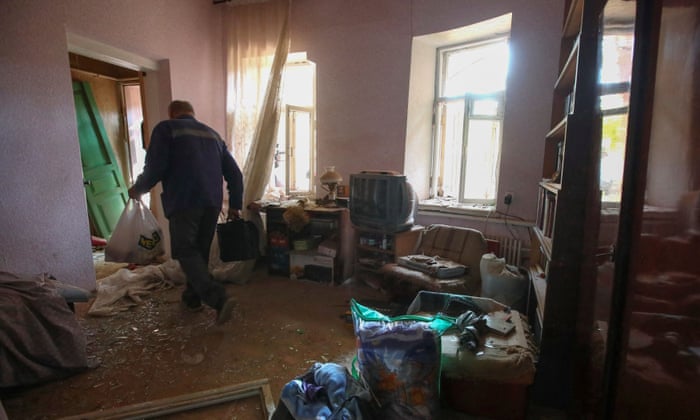 In Kharkiv, Ukraine, a local resident carries items out of an apartment damaged by a Russian military strike, as Russia’s attack on Ukraine continues