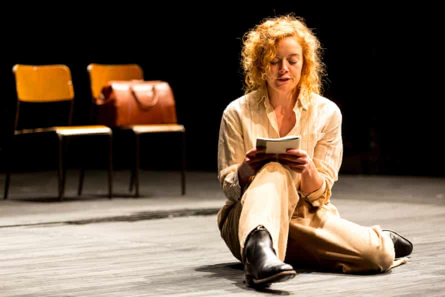A woman sits on a wooden floor reading a book