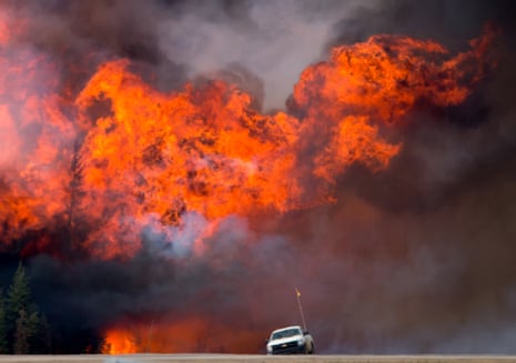 A wildfire burns behind an abandoned truck on Alberta Highway 63 near Fort McMurray in May 2016. 