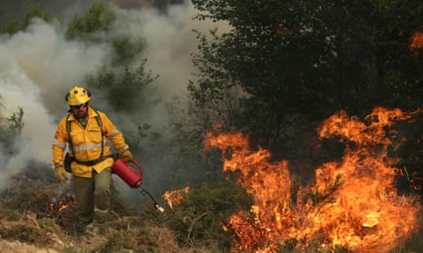 A firefighter lights a controlled fire to bring wildfires under control