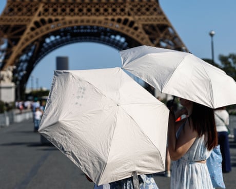 Two people hold white umbrellas near the Eiffel Tower