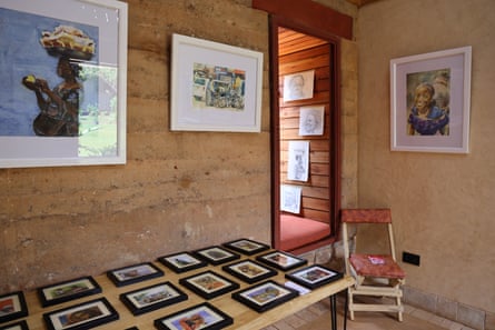 Framed photographs of paintings are hung on a wall and laid out of a table.