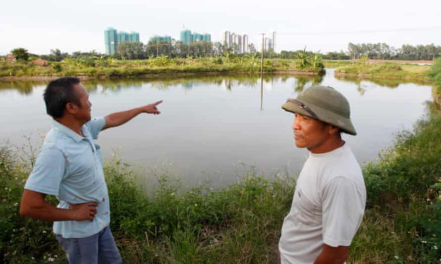 Dang Van Dat points to an Ecopark construction site as he stands with veteran Le Dung on an area involved in April 24’s land seizure in Van Giang district<br>Dang Van Dat.