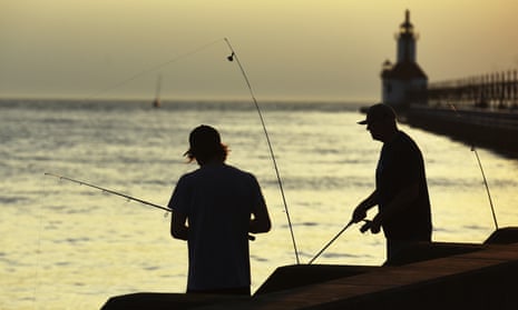 The sun sets as fishermen try their luck along the St Joseph River on 6 July 2022, in St Joseph, Michigan.