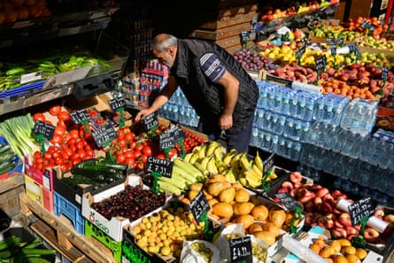 A shopkeeper tends to fruit in a grocery shop in London