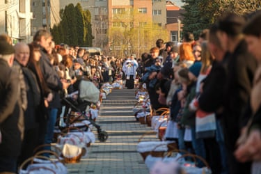 Two rows of people having Easter baskets blessed by a priest in Transylvania