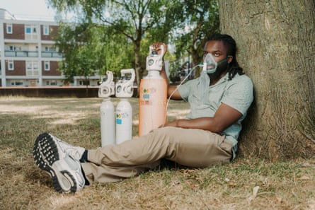 Morgan Ofori wearing his oxygen mask and sitting under a tree with three gas canisters