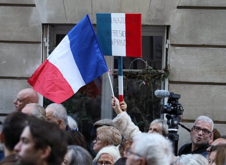 A supporter of former French President Nicolas Sarkozy holds a banner which reads ‘shame on justice’ outside his home in Paris, on the day of Sarkozy’s imprisonment.