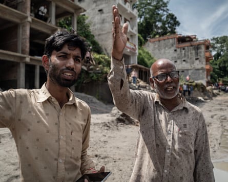 Ashok Chaurasia and an older man in a muddy street with damaged buildings behind them.