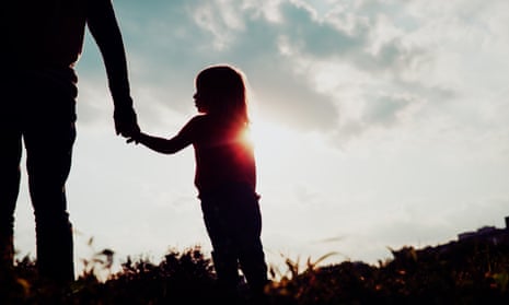 silhouette of little girl holding parent's hand at sunset sky