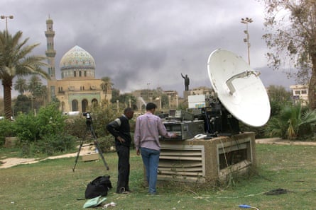 Journalists in the garden of Palestine Hotel in Baghdad on 30 March 2003, with a view of the soon-to-be-toppled statue.