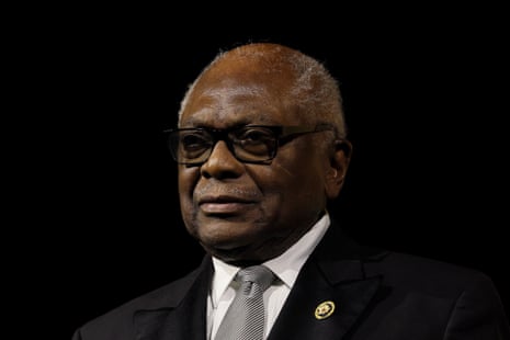 Representative James Clyburn in a dark suit, striped tie, and glasses smiles against a dark background