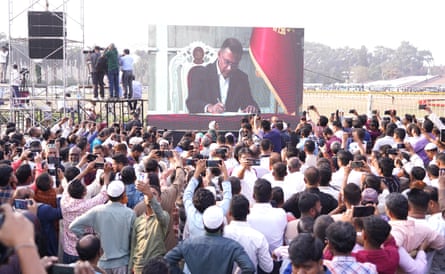 People watch the swearing-in ceremony of Tarique Rahman on a big screen in Dhaka.