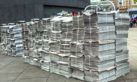 Rows of newspaper stacks lined up on a pavement, London, England, UK.