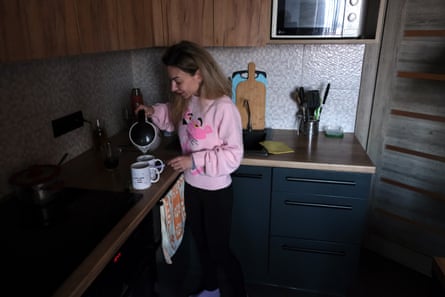A woman pours hot water from a kettle.