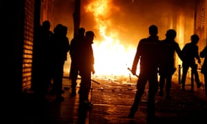 Spanish police officers stand in front of burning rubbish bins during clashes in Madrid on Thursday night.