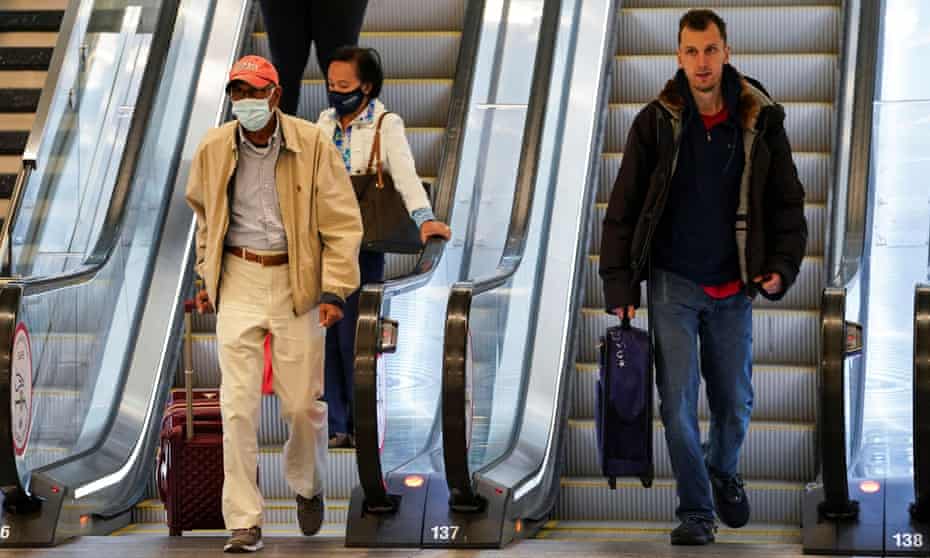 Masked and unmasked travelers ride escalators at Ronald Reagan Washington national airport in Arlington, Virginia, on Tuesday.