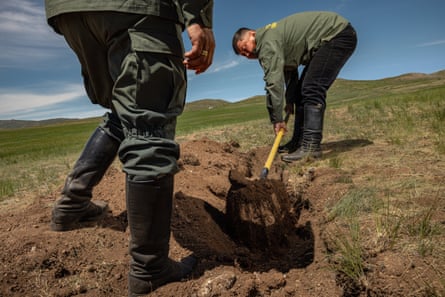 Two men dig a trench by hand