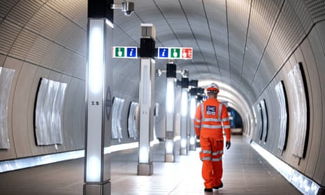 A man in Crossrail hi-visibility overalls walking away from the camera down a newly finished walkway