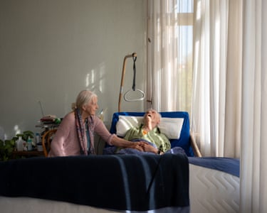 Crista lays her arm over her husband’s as he lies back facing the ceiling
