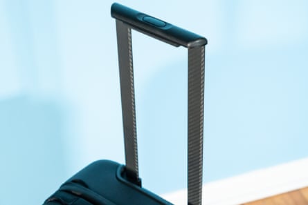 Closeup of handle on suitcase beside blue wall