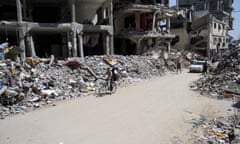 Man cycles past destroyed buildings