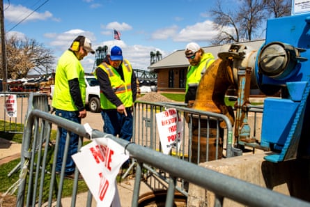 men in reflective vests work to prevent flood waters from coming up