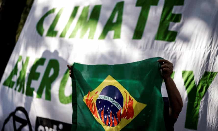 A protester holds a Brazilian flag depicting the country’s emblem in flames in front of the Brazilian Embassy during a demonstration organised by Extinction Rebellion activists in Brussels, 26 August 2019.