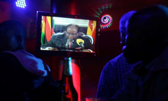 Zimbabweans watch president Robert Mugabe's address on a TV at a bar in Harare.