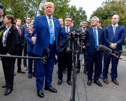 Men in suits stand outside by microphones, one man speaking