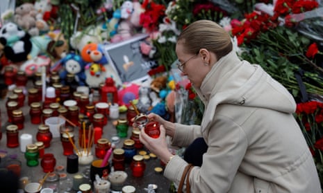A woman lights a candle at the makeshift memorial to the victims of a shooting attack set up outside the Crocus City Hall concert venue.