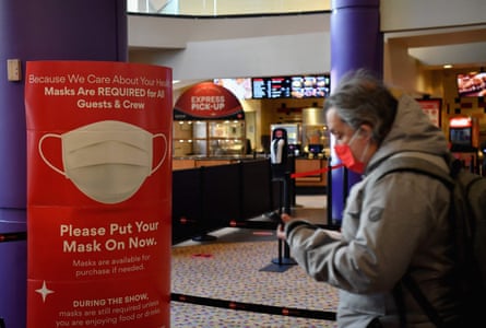 A red sign on a post inside a movie theater reminds patrons to wear their masks.