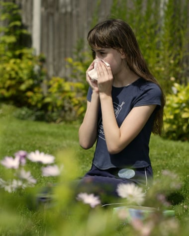Woman sitting on a lawn blowing her nose