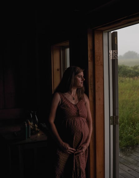 a pregnant woman wearing a polka-dot dress stands in the doorway and gazes outside