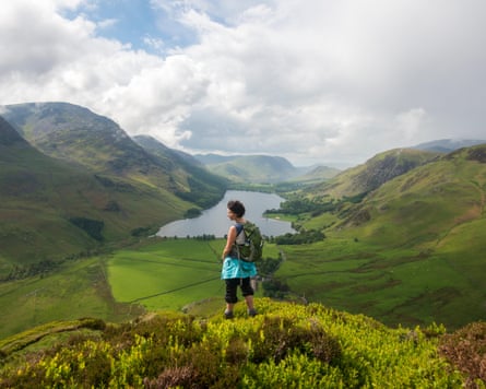 A woman looks out over Buttermere from Fleetwith Pike, Lake District National Park, Cumbria, UK