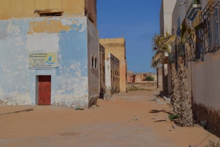Street scene with local architecture, sandy road and palm trees