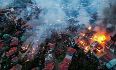 Aerial view of a village shrouded in smoke with several buildings ablaze
