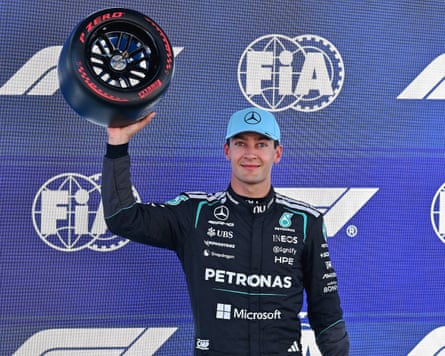 George Russell holds up an F1 racing tyre