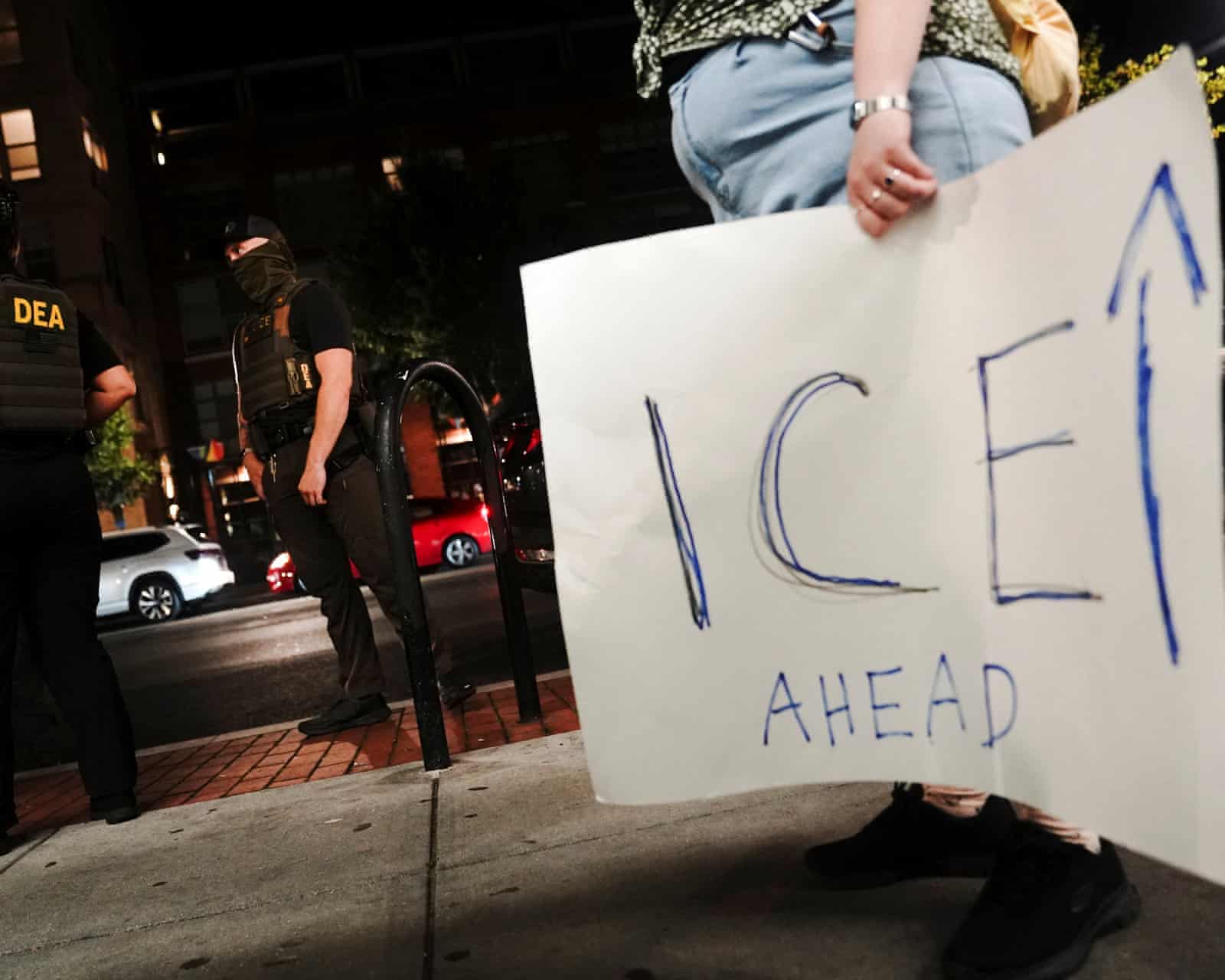 Protester holds sign referencing ICE agents after Trump DC federal takeover